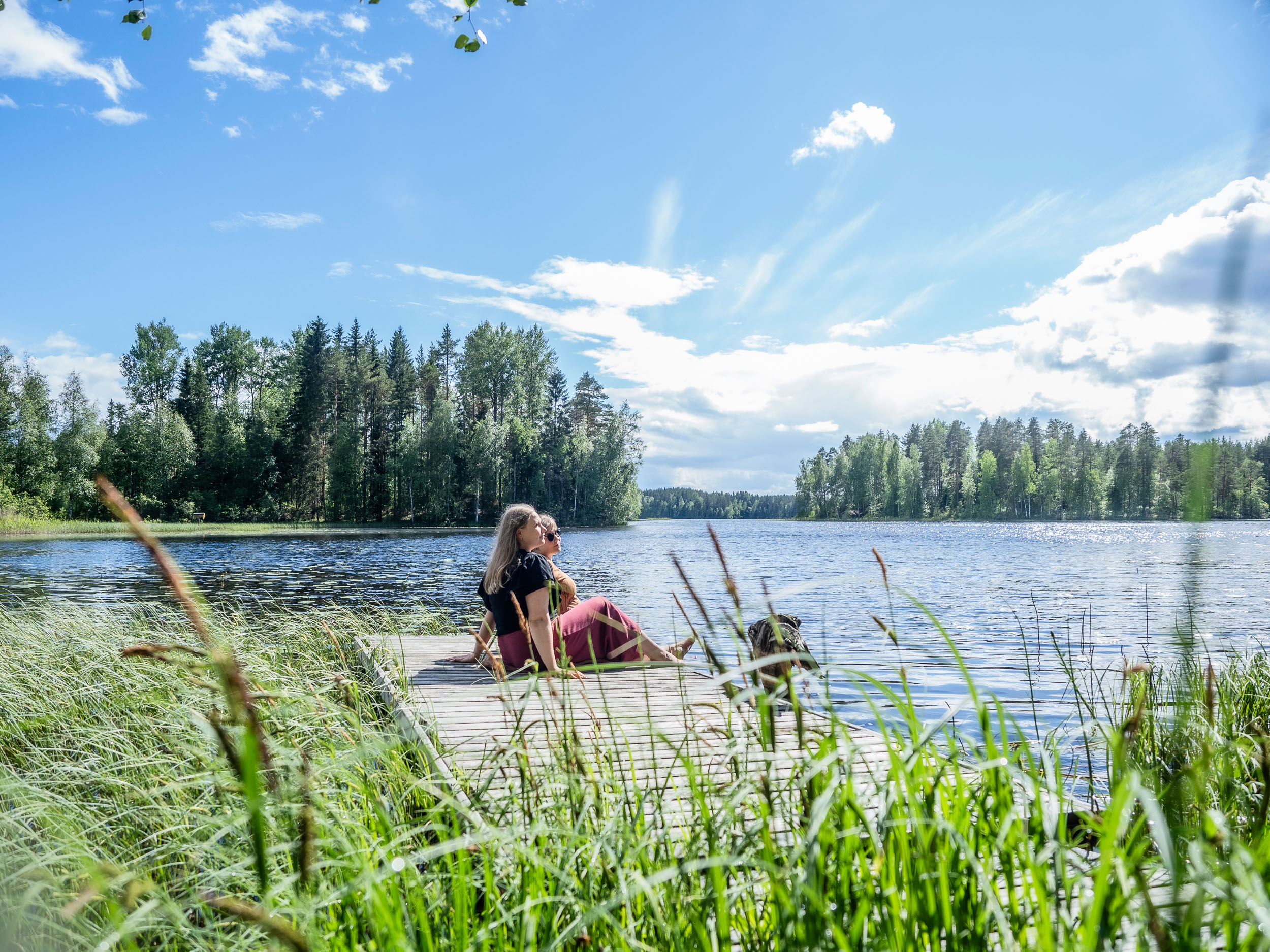 Naiset istumassa laiturilla ja nauttimassa kesästä